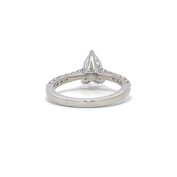 White gold pear-shaped diamond engagement ring with a diamond band on a white background.