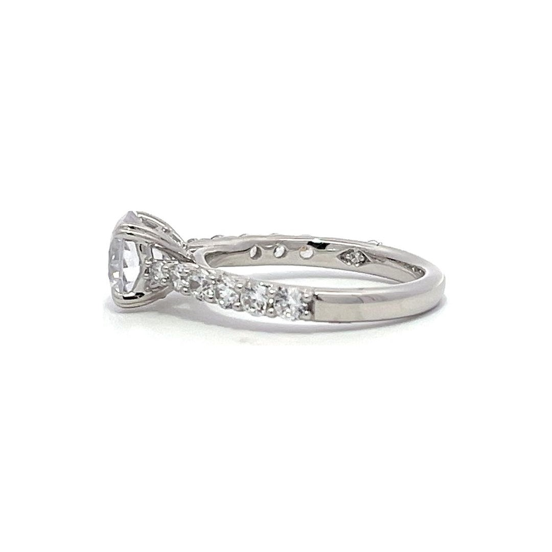 White gold round-shaped diamond engagement ring with a diamond band on a white background.