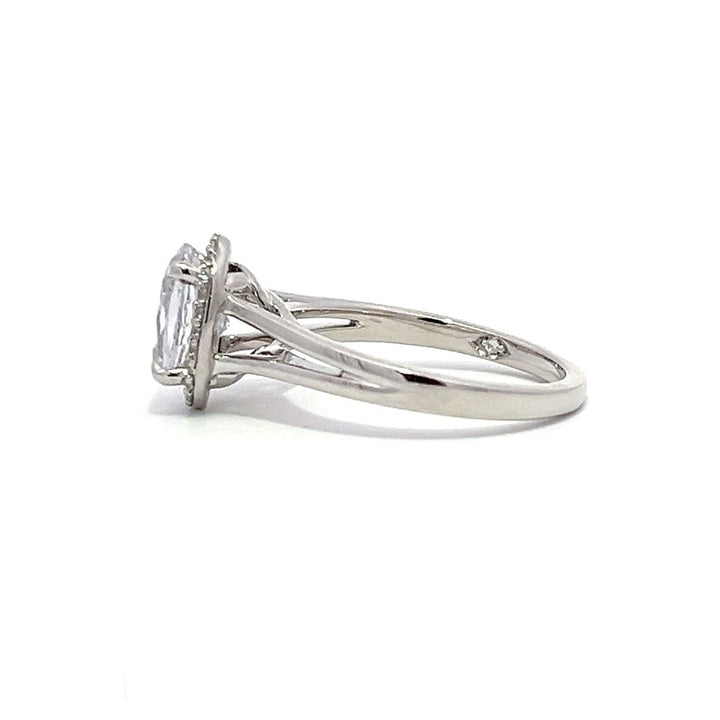 White gold oval diamond engagement ring with a halo setting and split shank on a white background