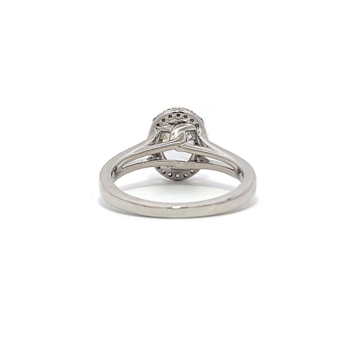 White gold oval diamond engagement ring with a halo setting and split shank on a white background