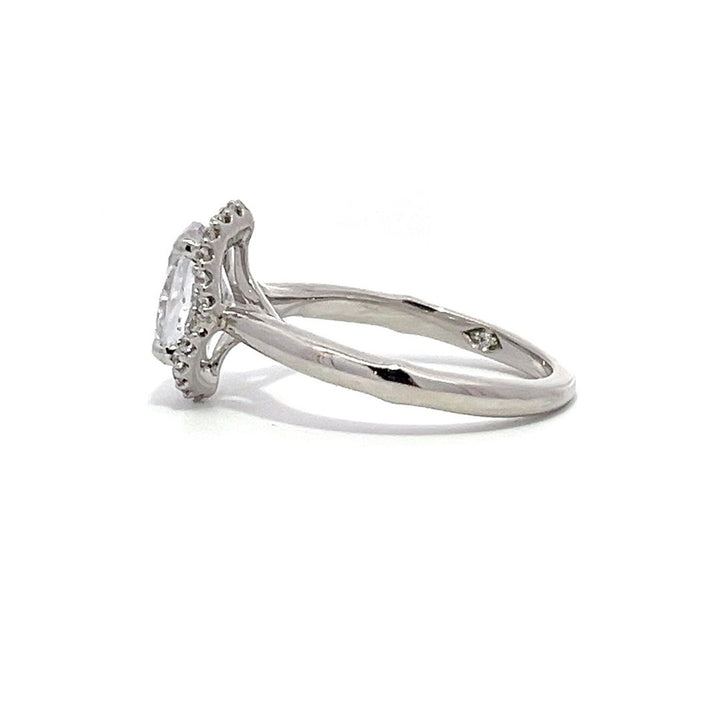 White gold oval diamond engagement ring with a halo setting on a white background