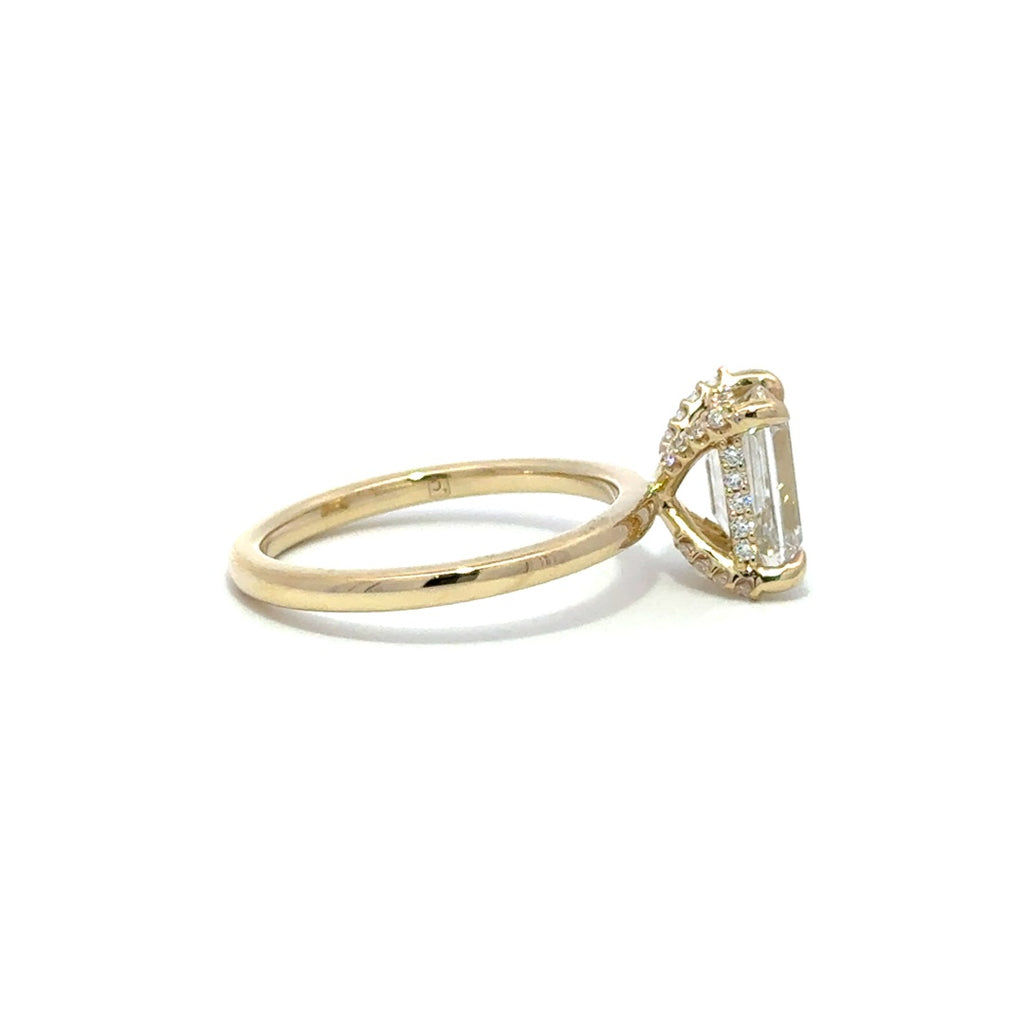 Side view of yellow gold engagement ring with a center emerald cut diamond.