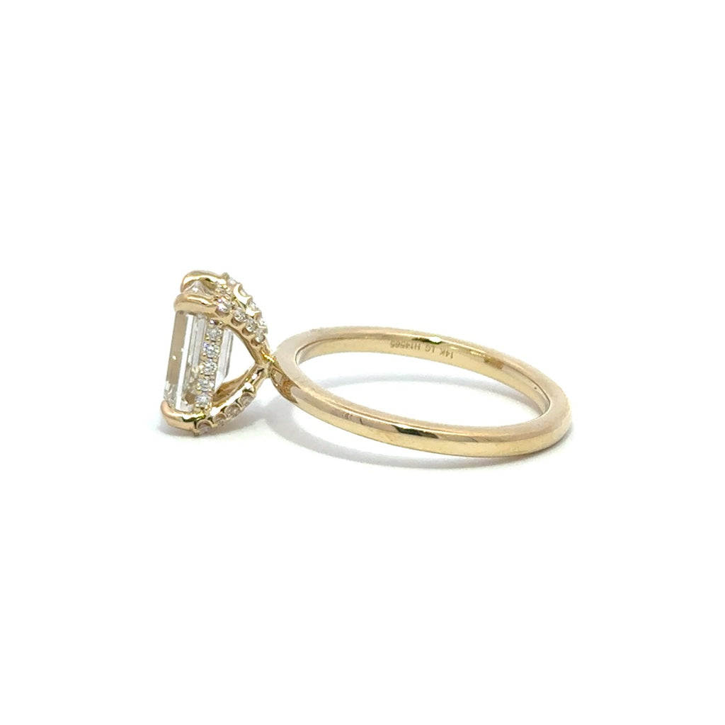 Side view of yellow gold engagement ring with a center emerald cut diamond.