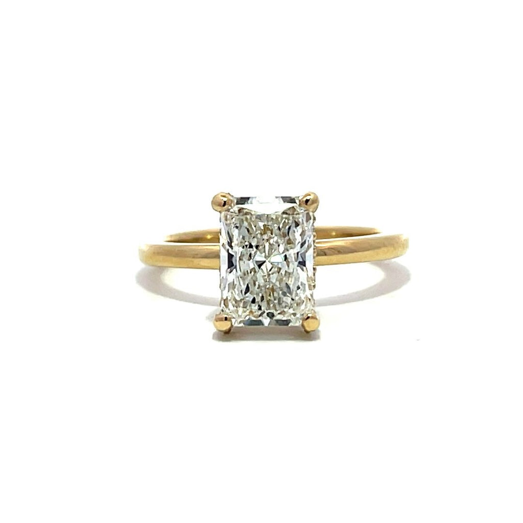 Yellow gold engagement ring with a radiant-cut diamond center stone on a white background.