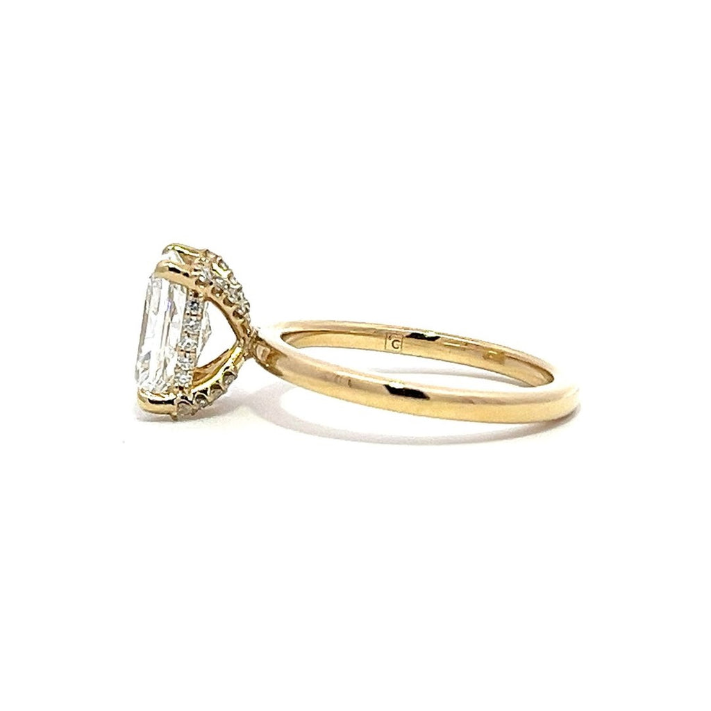 Yellow gold engagement ring with a radiant-cut diamond center stone on a white background.