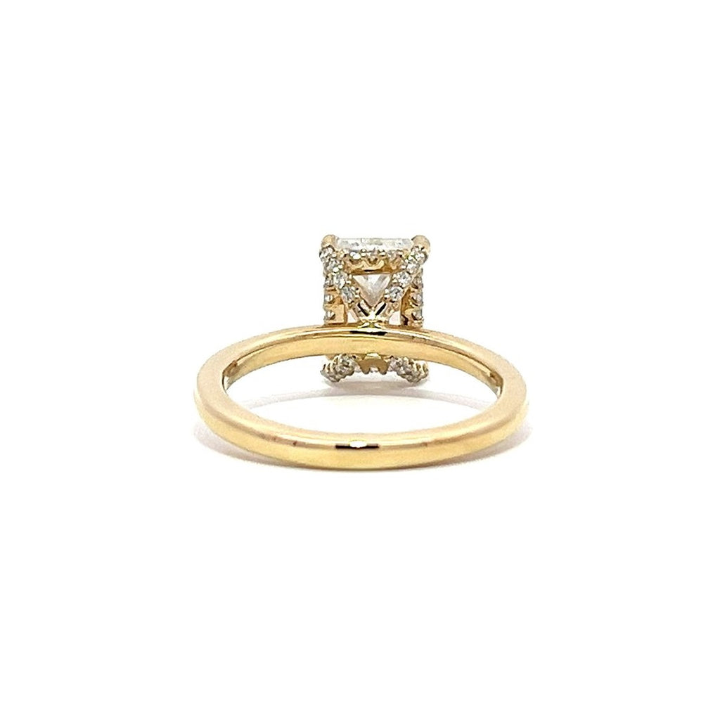 Yellow gold engagement ring with a radiant-cut diamond center stone on a white background.