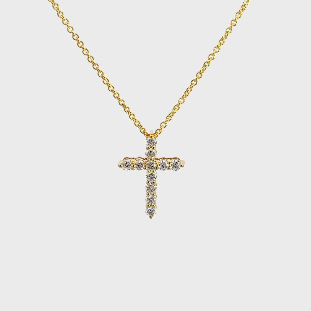 Yellow gold diamond cross necklace on a white background