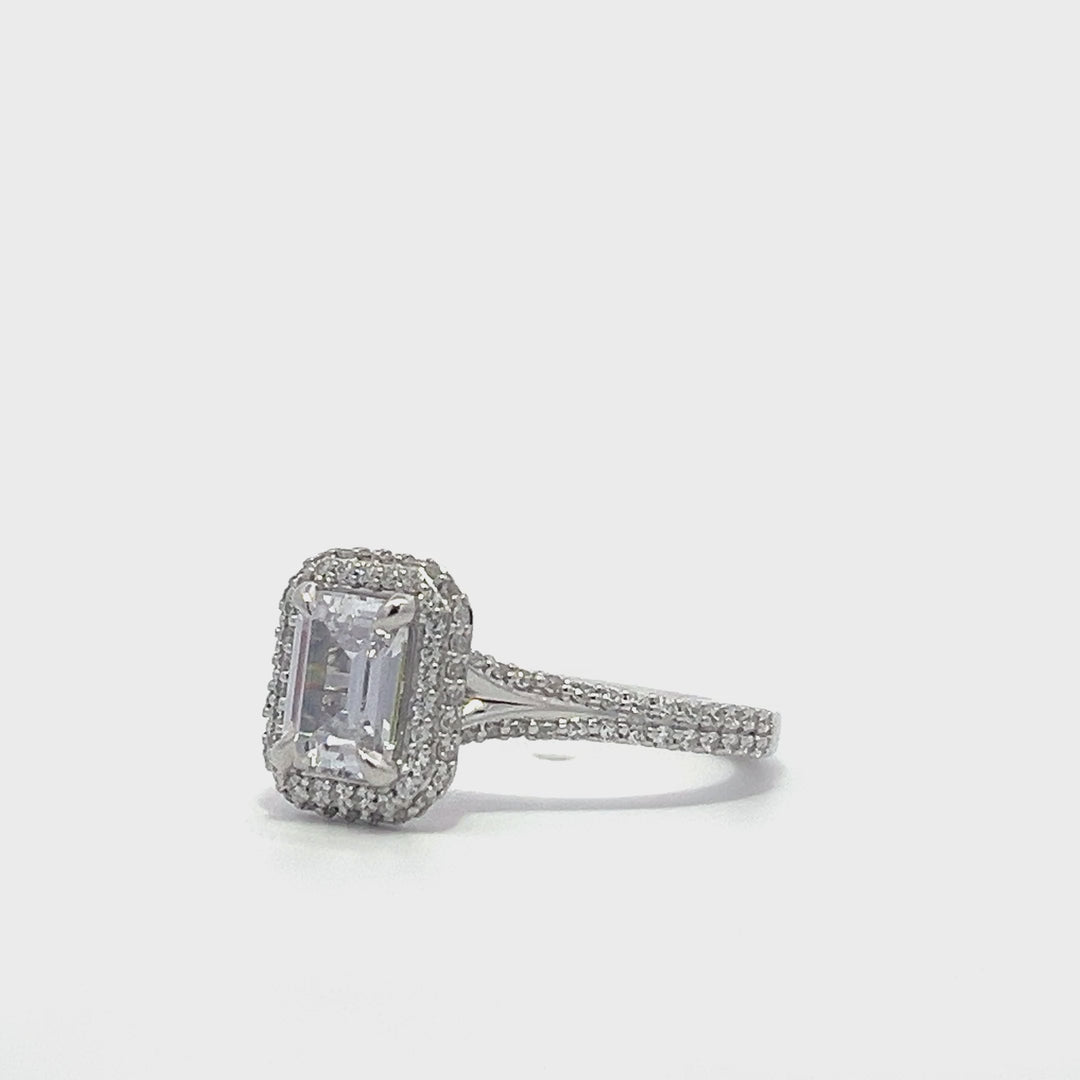 Silver emerald-cut engagement ring with a double halo setting on a white background