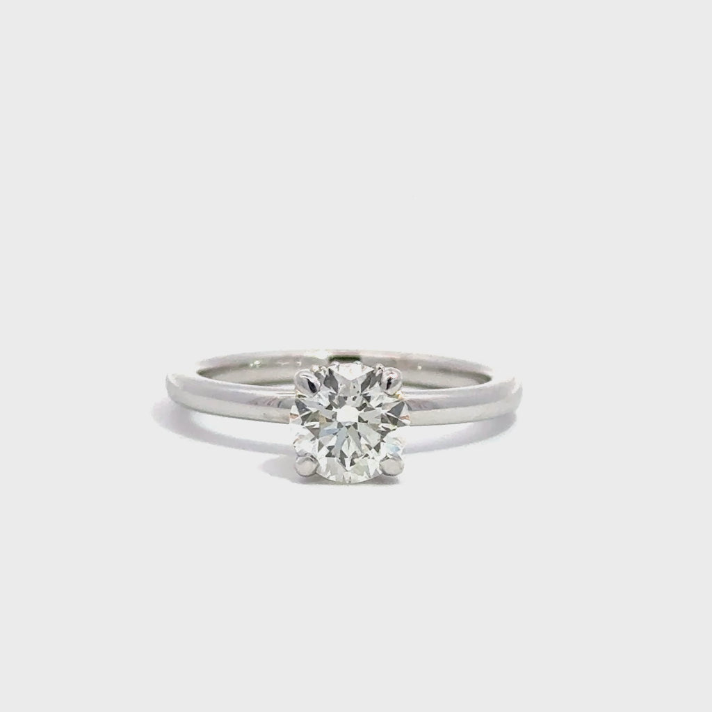 Silver solitaire ring with round cut diamond centerpiece against white background