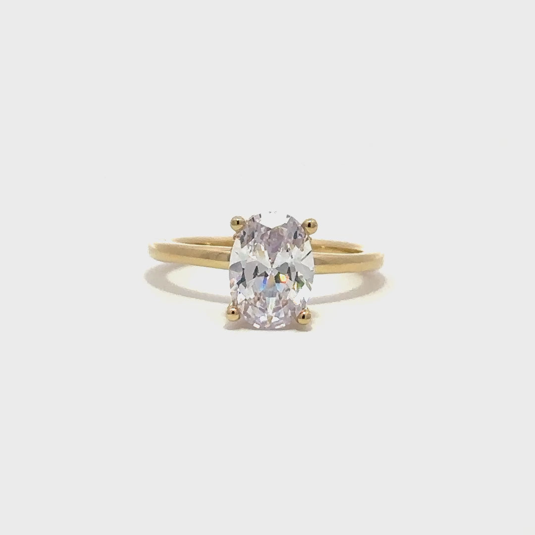 Gold ring wth oval cut diamond centerpiece on a white background