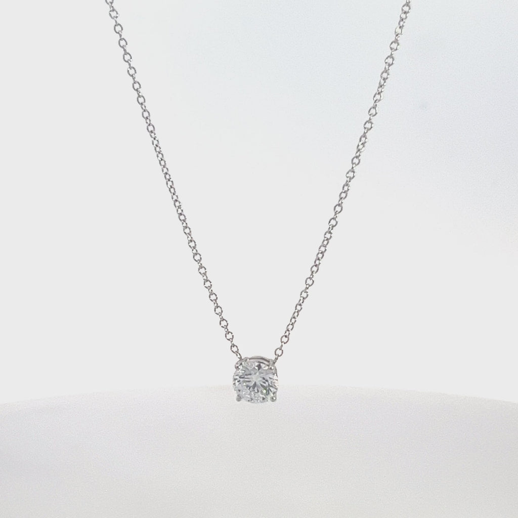 Silver necklace with a round diamond solitaire pendant on a white background.