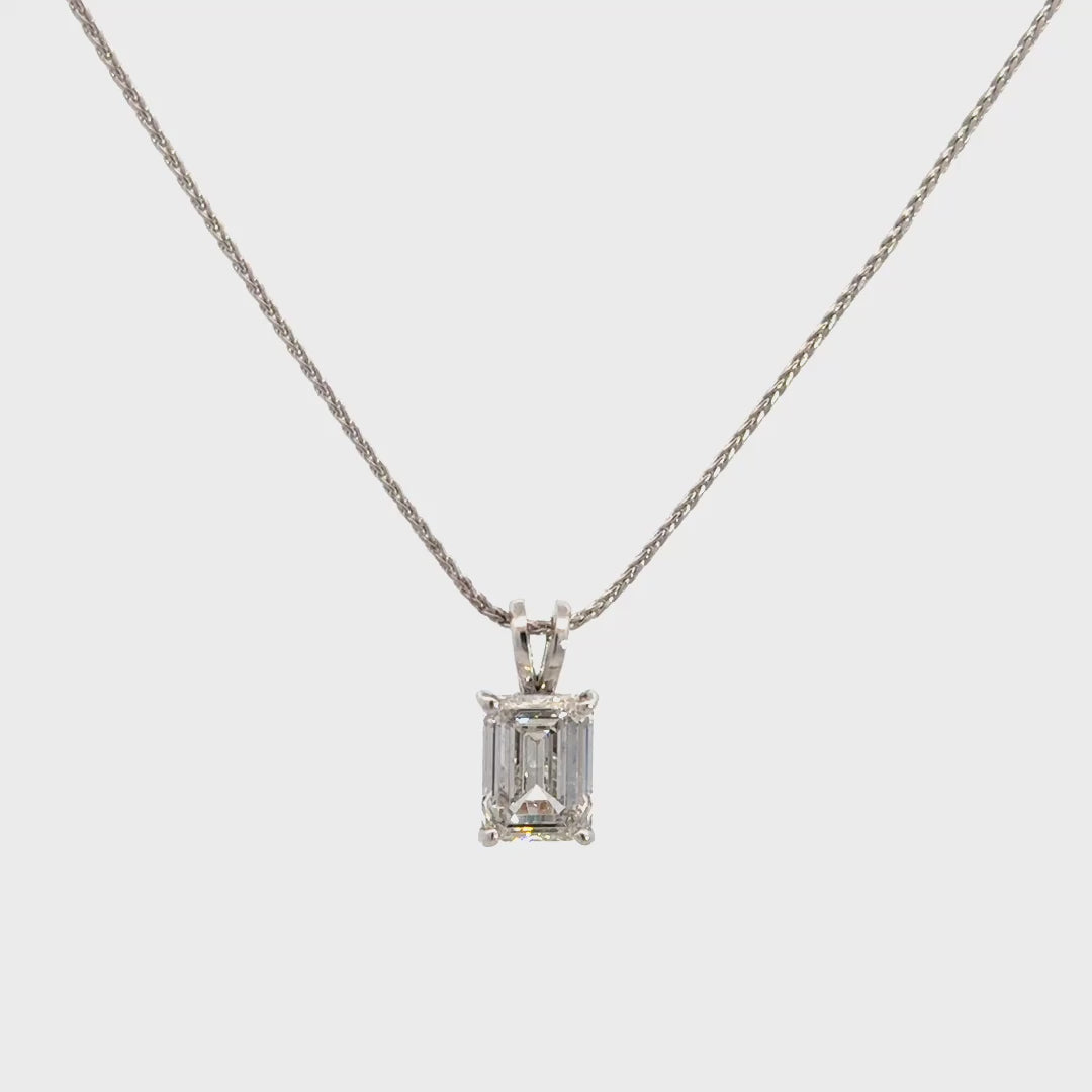 Silver necklace with a emerald-cut diamond in a four-prong setting pendant on a white background.