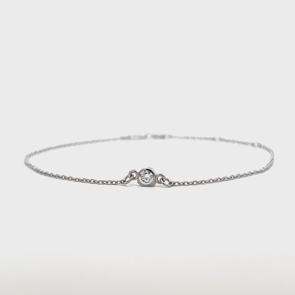 Silver bracelet with a single diamond pendant on a white background.