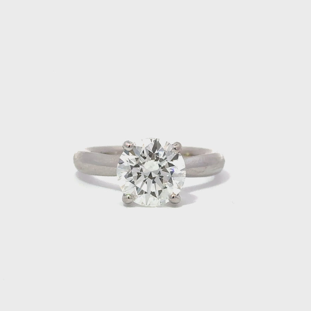 Silver engagement ring with a round-cut center diamond.