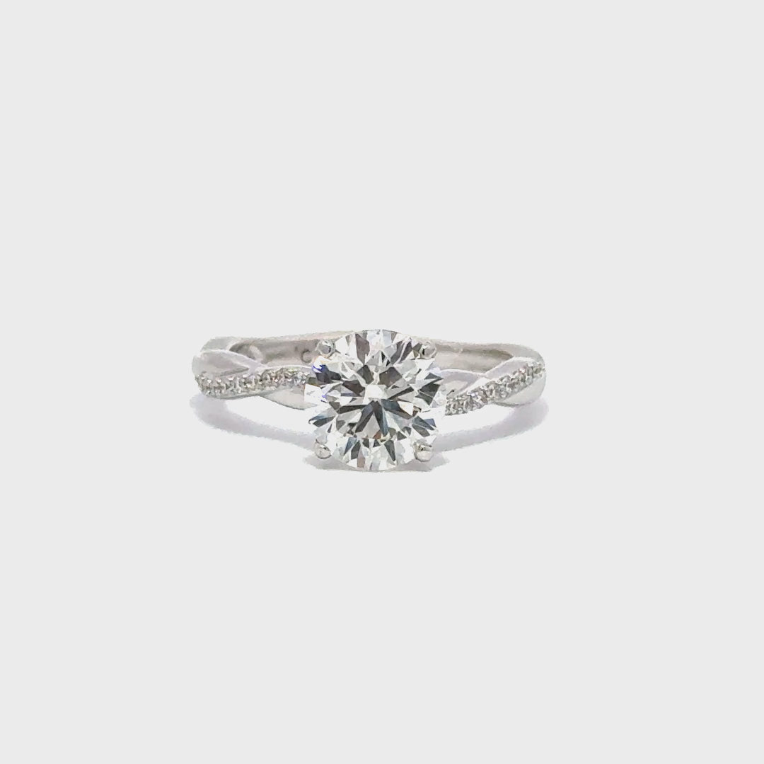 Silver engagement ring with a round-cut center diamond.