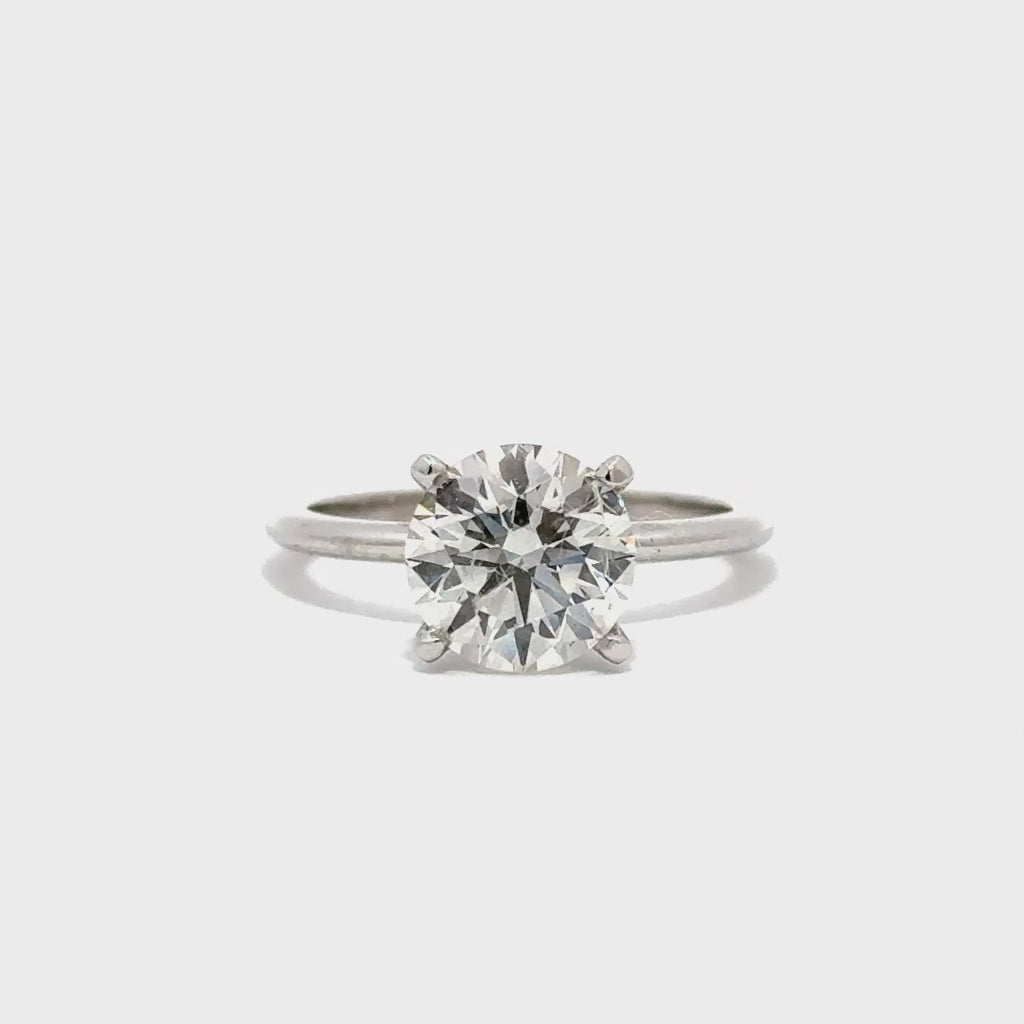 Silver solitaire engagement ring with a round-cut diamond center stone on a white background.