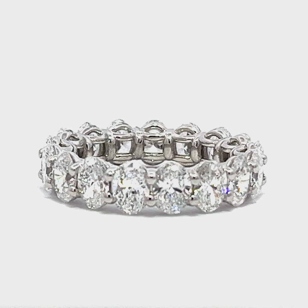 Silver eternity band with oval-shaped diamonds on a white background.