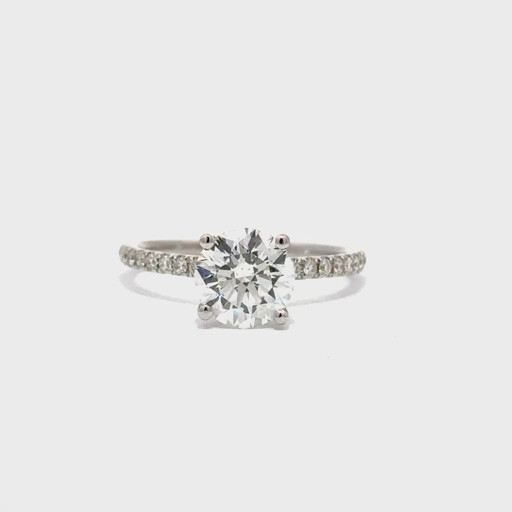 Silver gold solitaire engagement ring with a round cut diamond center stone on a white background.