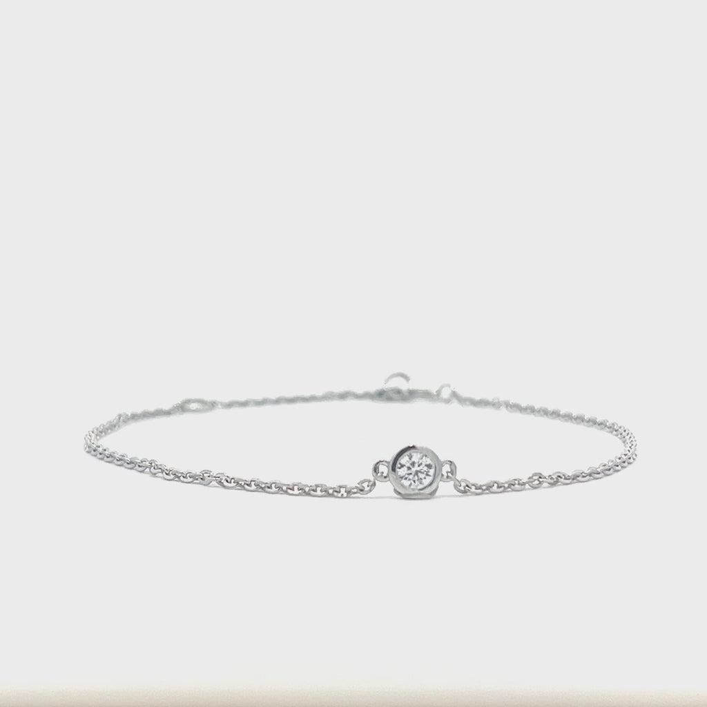 Silver bracelet with a single diamond pendant on a white background.