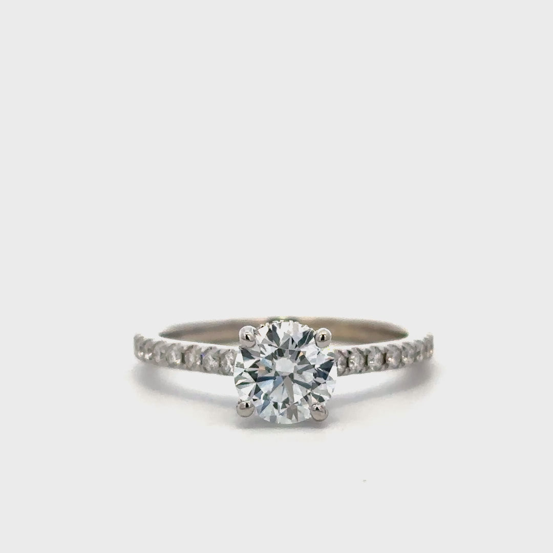 White gold diamond engagement ring with a halo setting and a diamond band on a white background.