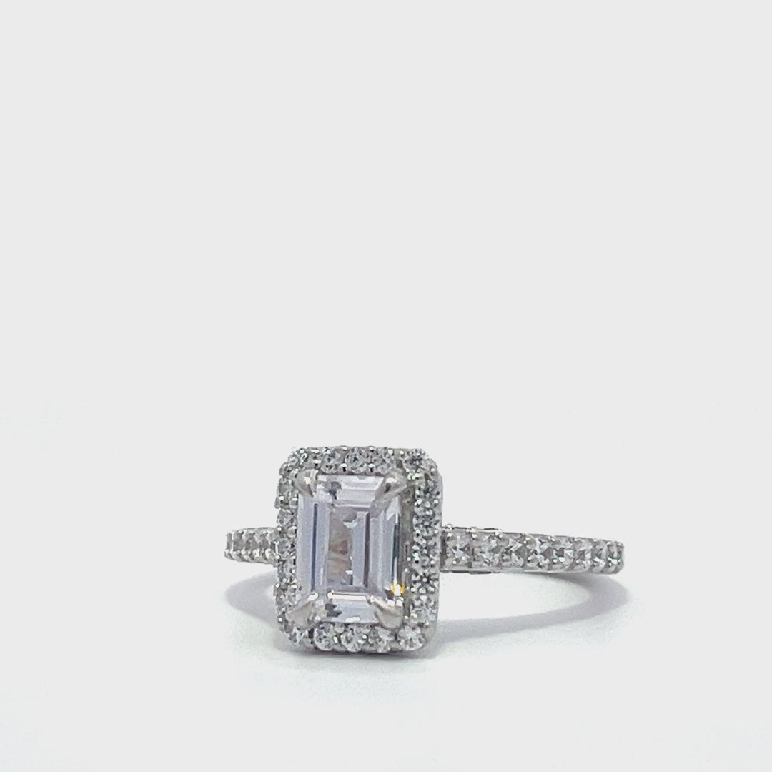 Silver emerald-cut engagement ring with a double halo setting on a white background