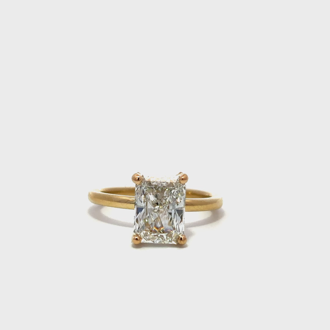 Yellow gold engagement ring with a diamond halo setting on a white background