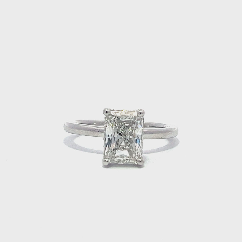 White gold engagement ring with a radiant-cut diamond center stone on a white background.