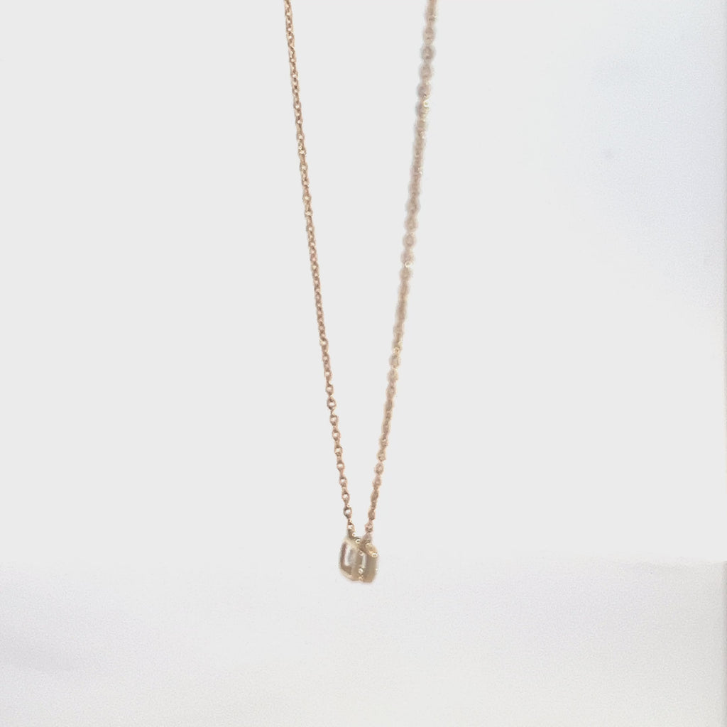 Yellow gold necklace with an emerald-cut diamond pendant on a white background.