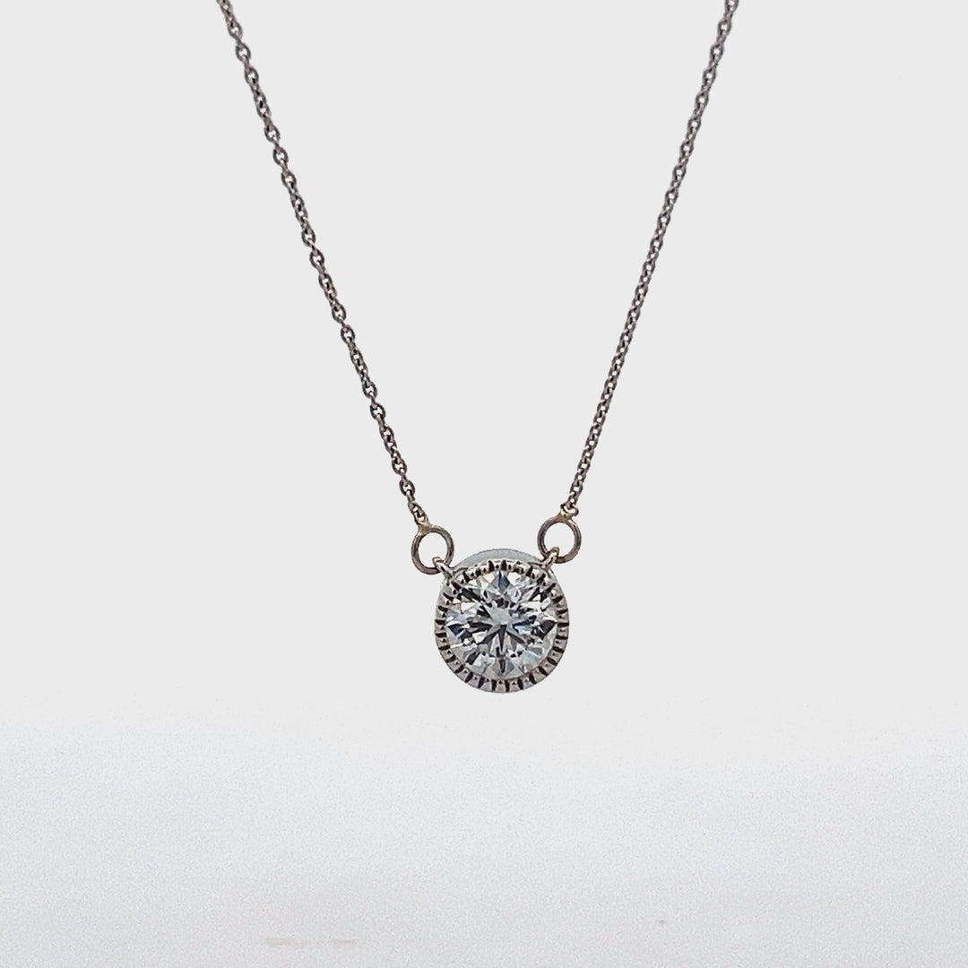 White gold necklace with a round diamond solitaire pendant on a white background.