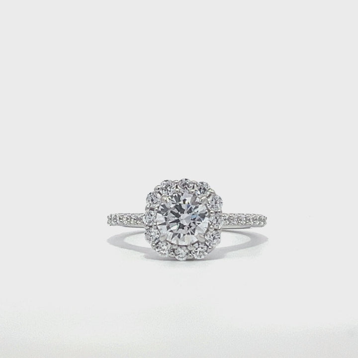 Silver engagement ring with a diamond halo setting and a diamond band on a white background