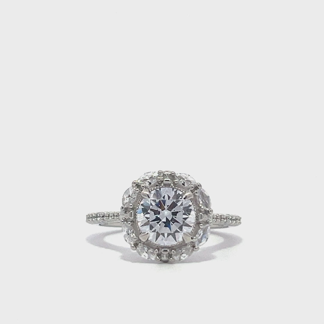 Silver engagement ring with a diamond halo setting and a diamond band on a white background