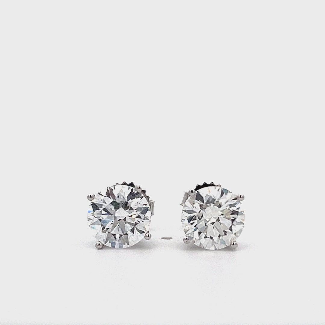 White gold stud earrings with round diamonds on a white background.