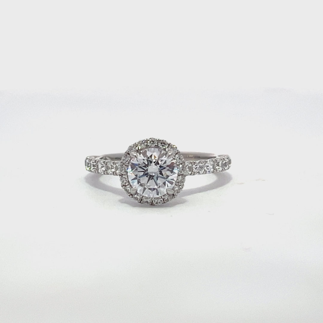 Silver engagement ring with a diamond halo setting and a diamond band on a white background