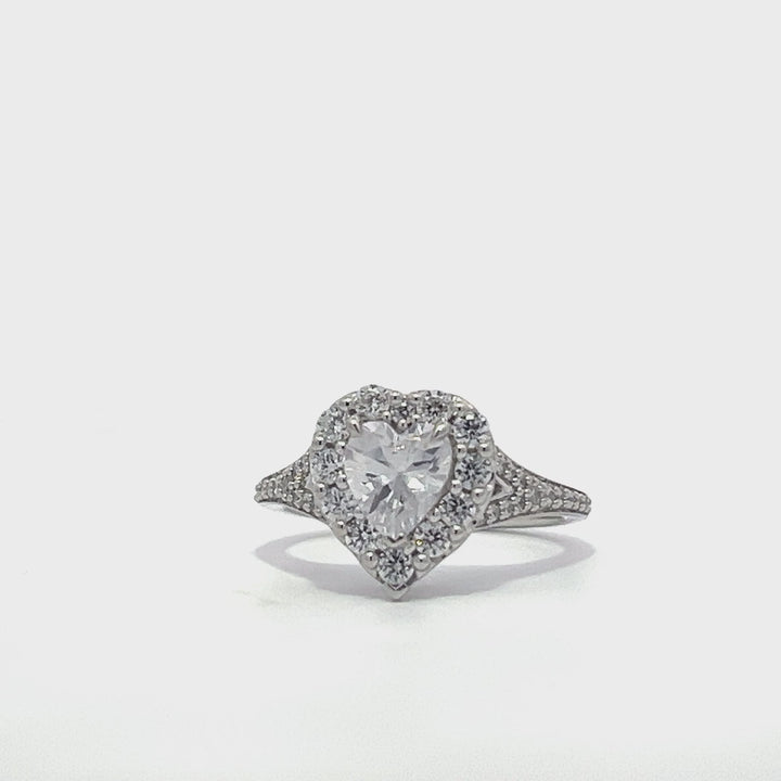 Silver heart-shaped diamond engagement ring with a halo setting and split shank on a white background.