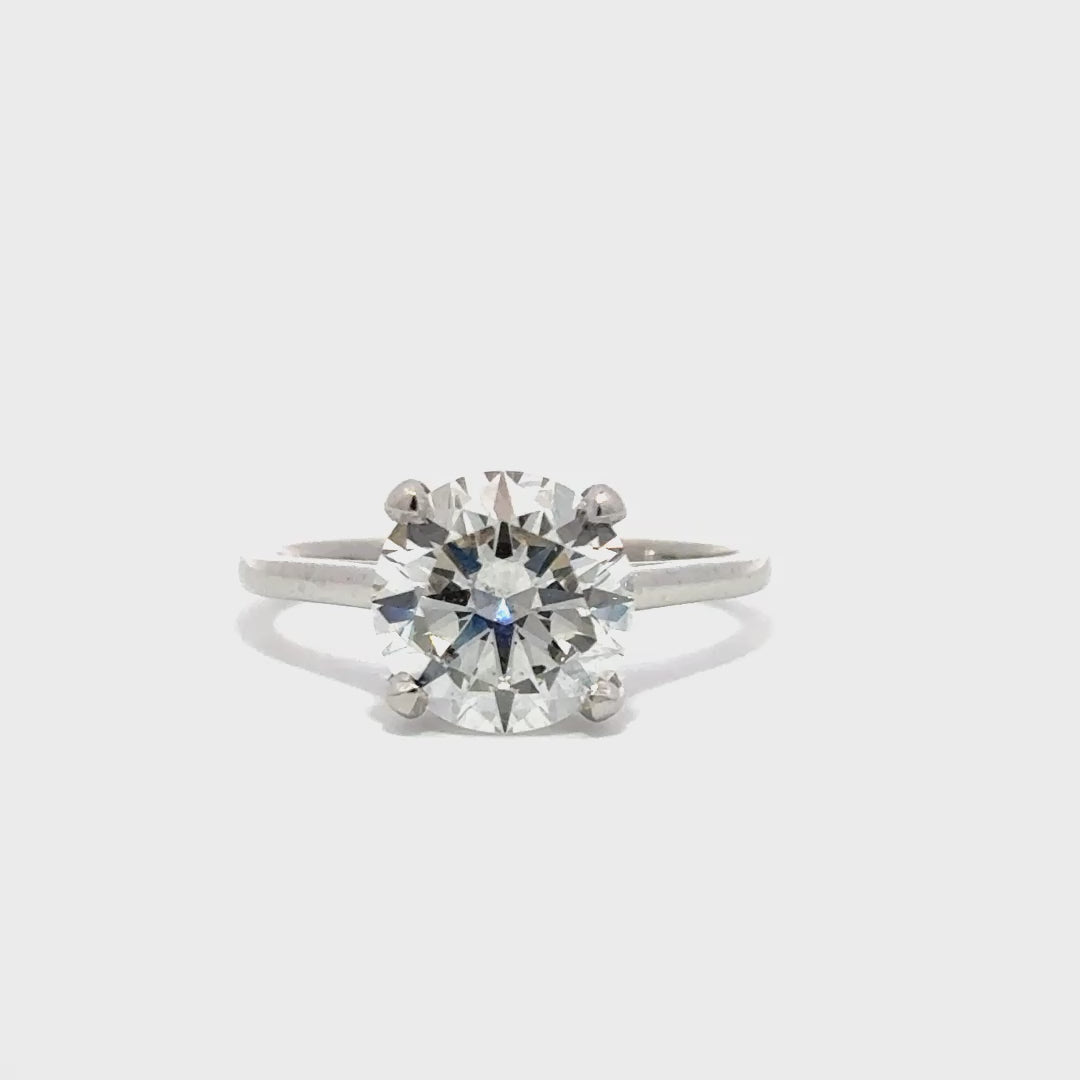 Silver solitaire engagement ring with a round-cut diamond center stone on a white background.