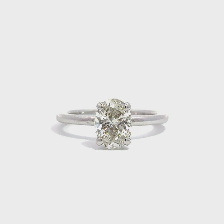 Silver solitaire ring with oval cut diamond centerpiece against white background