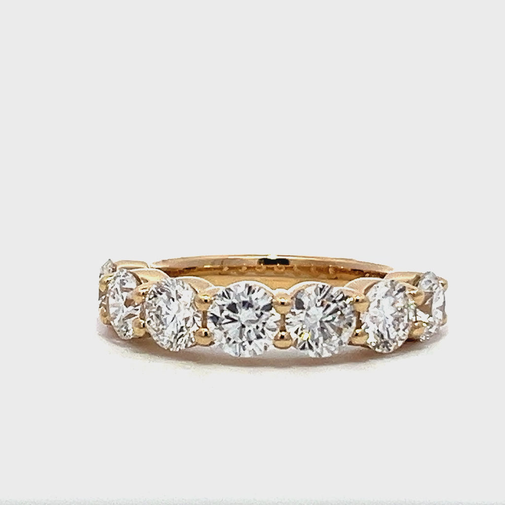 Yellow gold eternity band with round diamonds on a white background