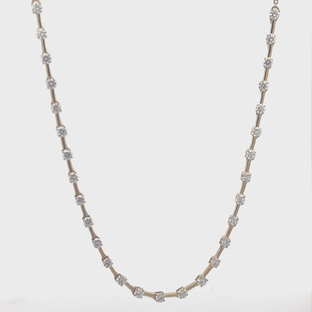 Yellow gold necklace with a row of round diamonds on a white background.